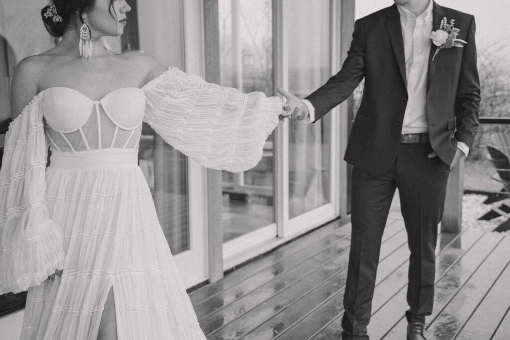 A couple standing on the porch of a cabin after their elopement in Pennsylvania. The bride is looking back at the groom, holding his hand.