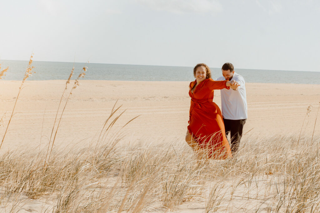 A couple dancing on a sandy beach on their elopement day, in a location by the ocean.