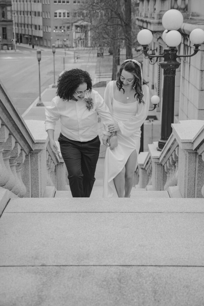 A couple walking up the stairs at their elopement location, holding hands.