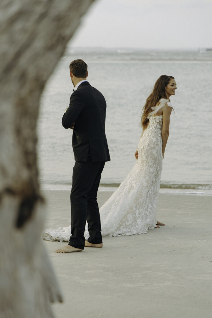 A couple on a beach in South Carolina, one of the best places to elope on the east coast. They're in their elopement attire, looking in opposite directions.